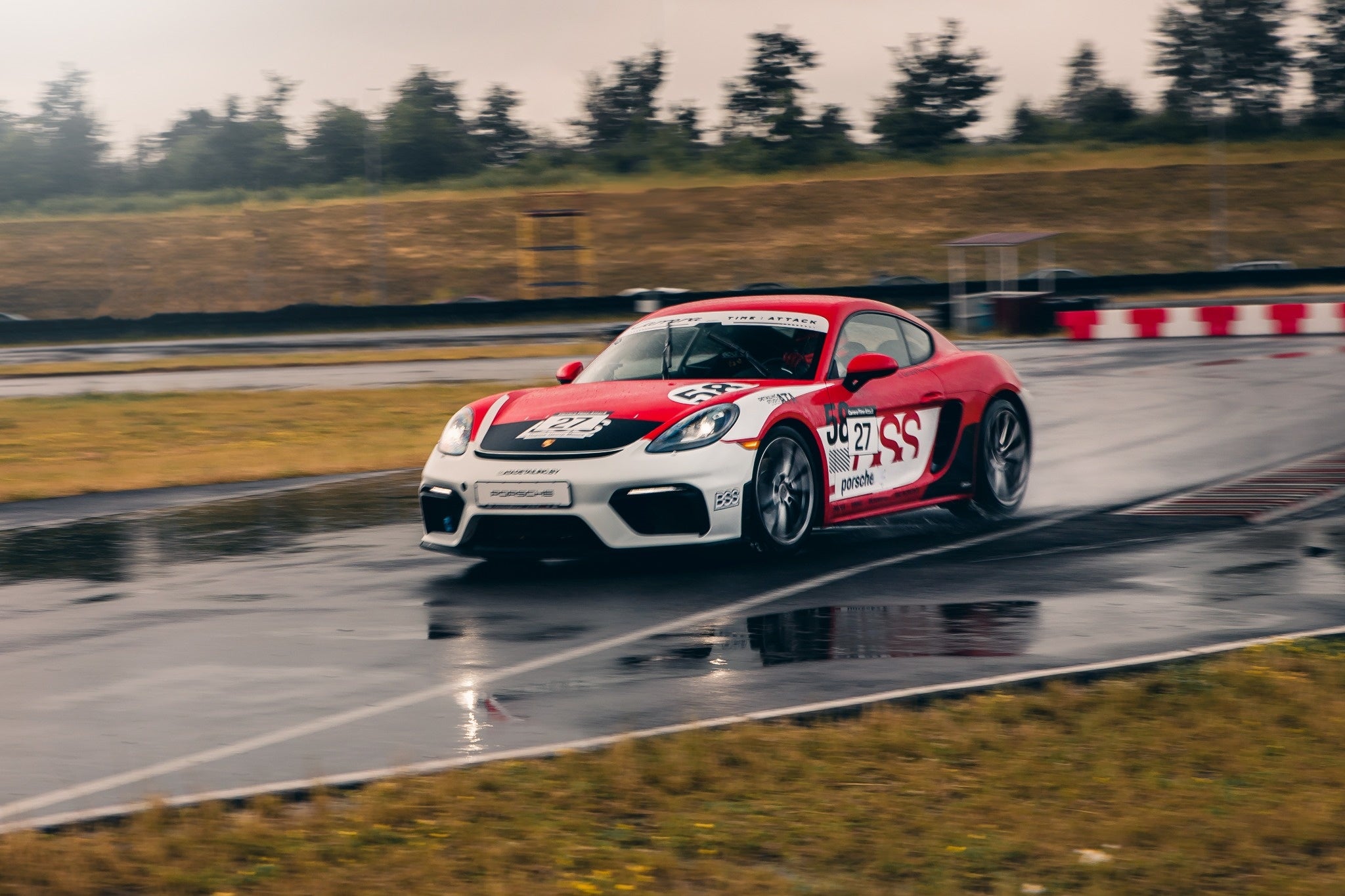 Red and white Porsche Cayman 58 on wet track